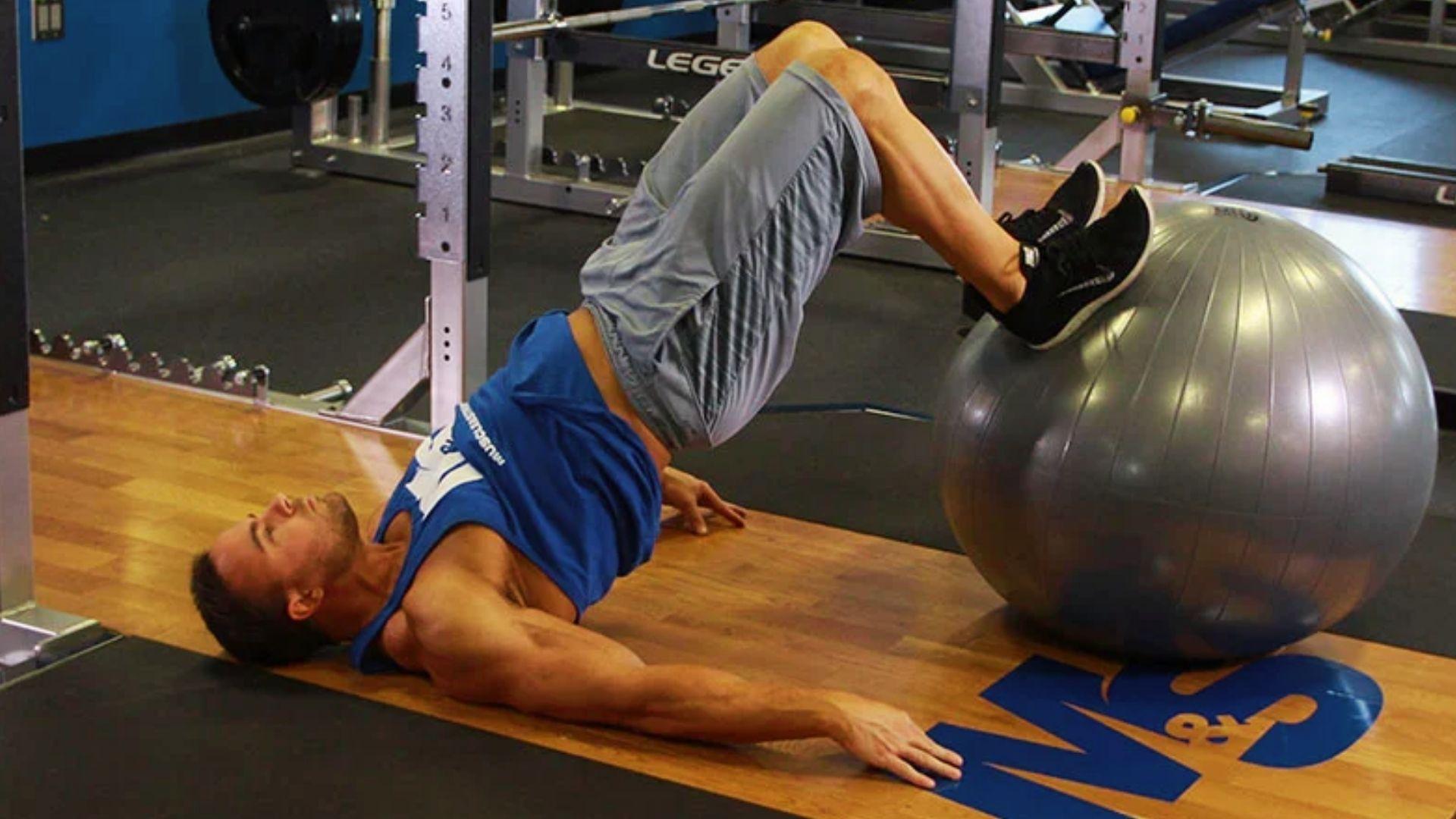 Person performing a stability ball hamstring curl exercise with proper form.
