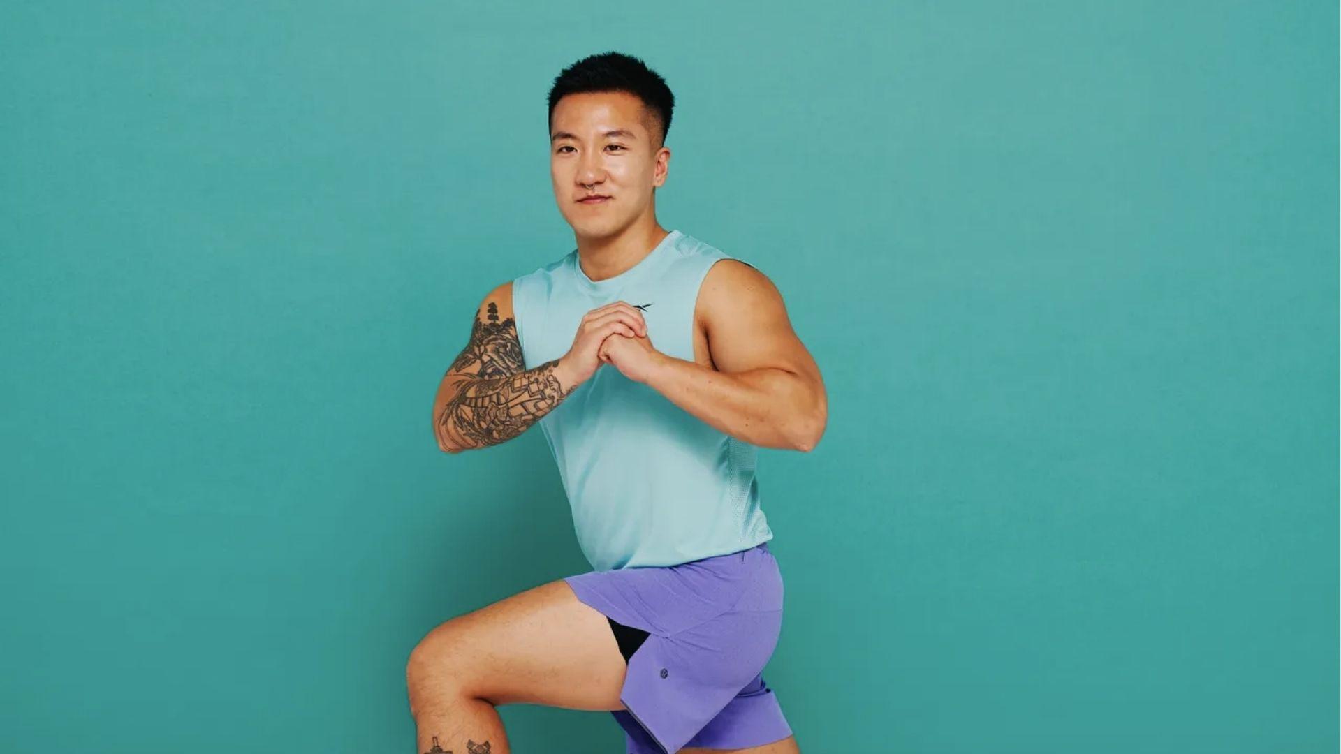 Man in blue tank performs lunges against teal wall for leg day in beginner calisthenics program