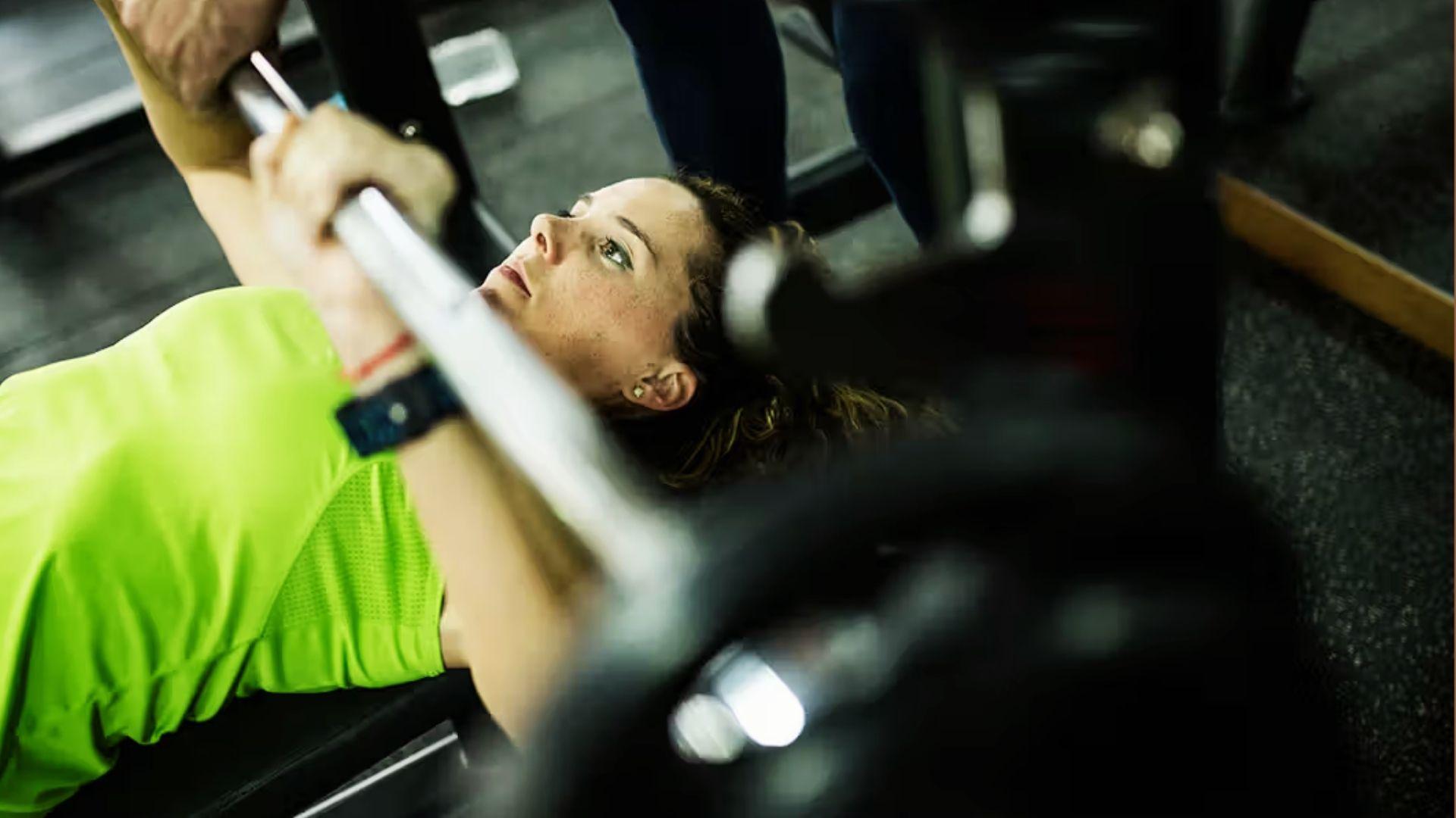 A person performing a bench press in the gym, demonstrating upper body strength and lifting performance.
