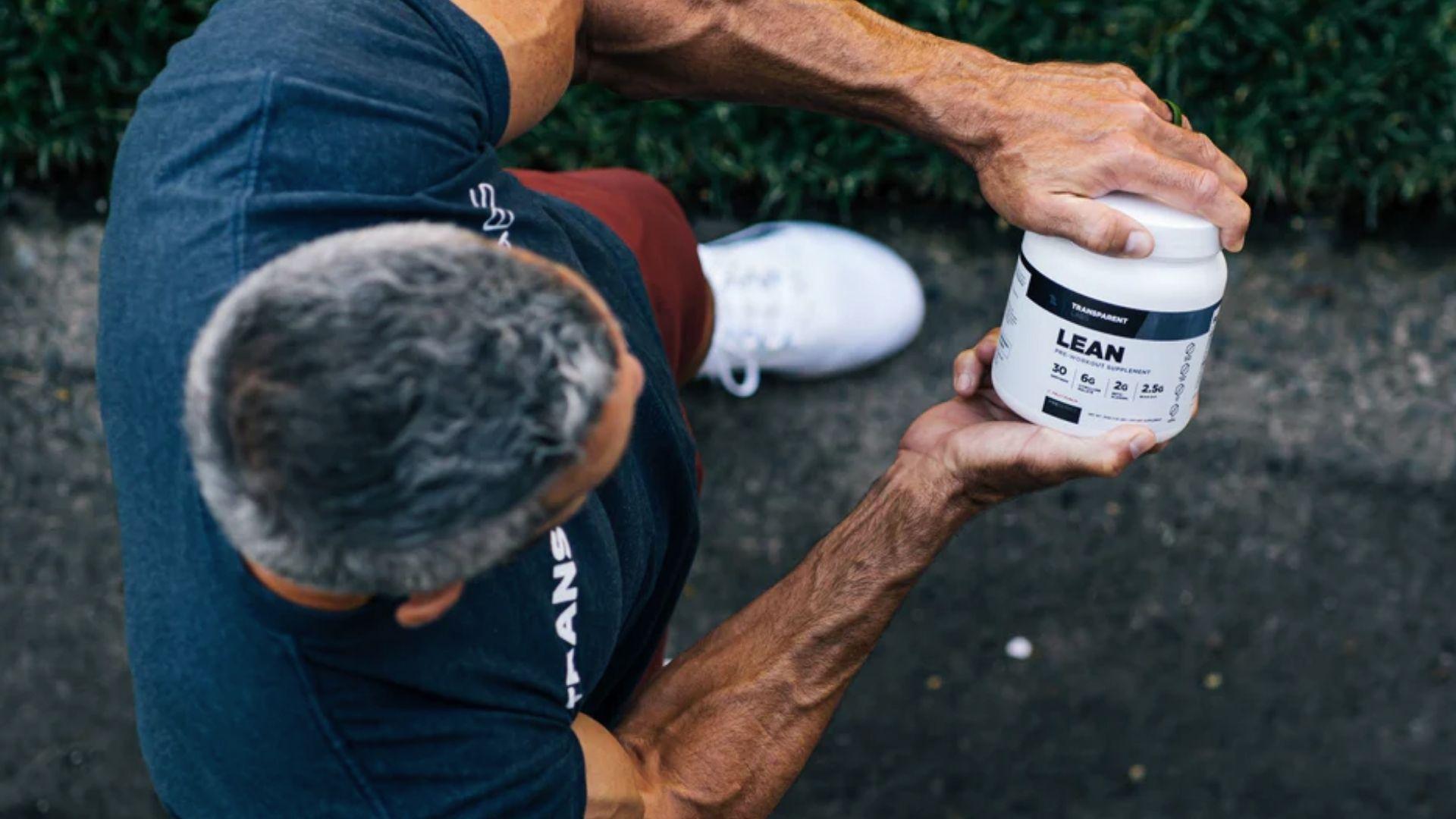 A person holding a pre-workout supplement in a gym, representing energy support for weight loss workouts.