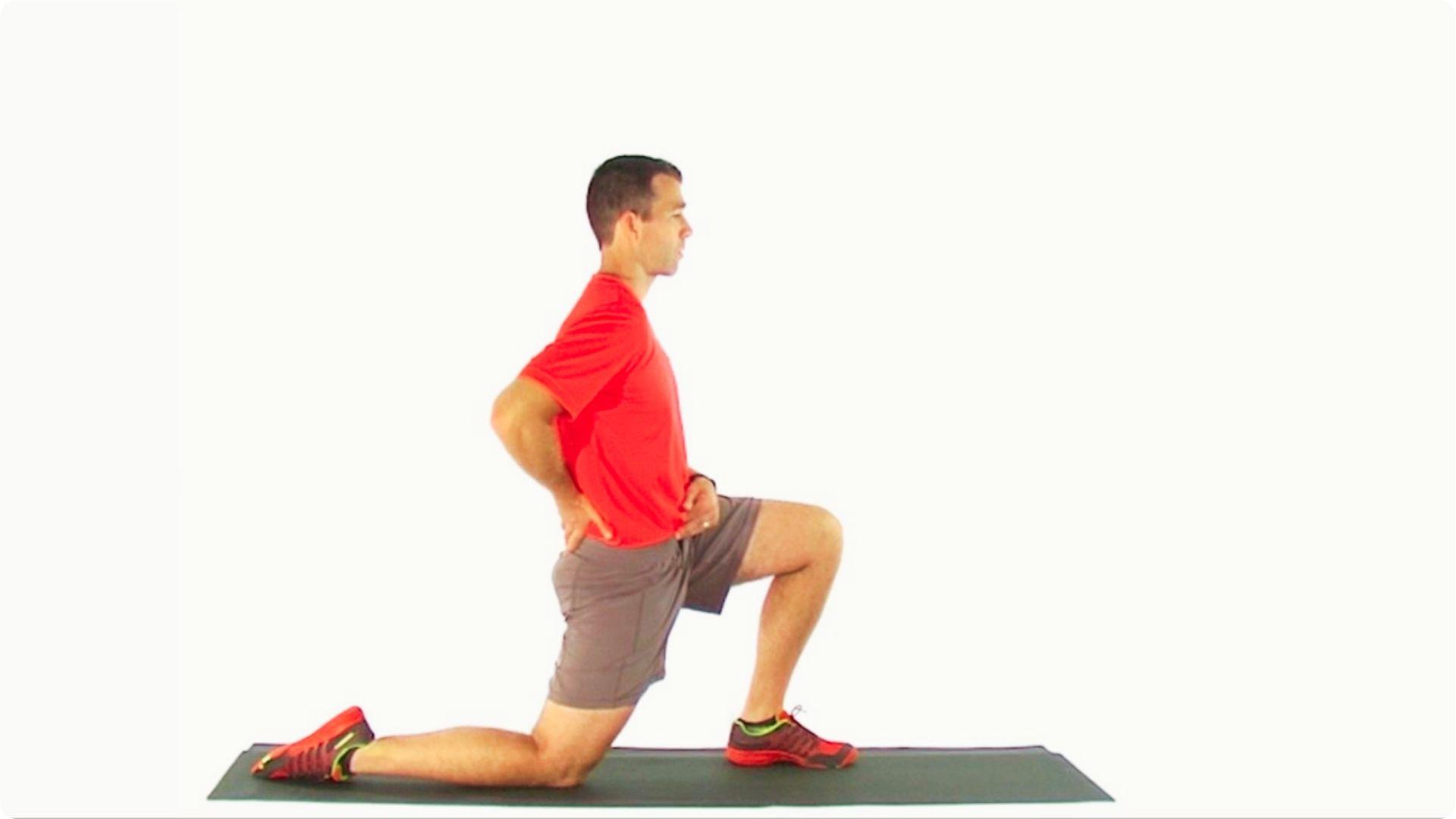 Man in red shirt demonstrating a kneeling hip flexor stretch on a mat with hands on hips.
