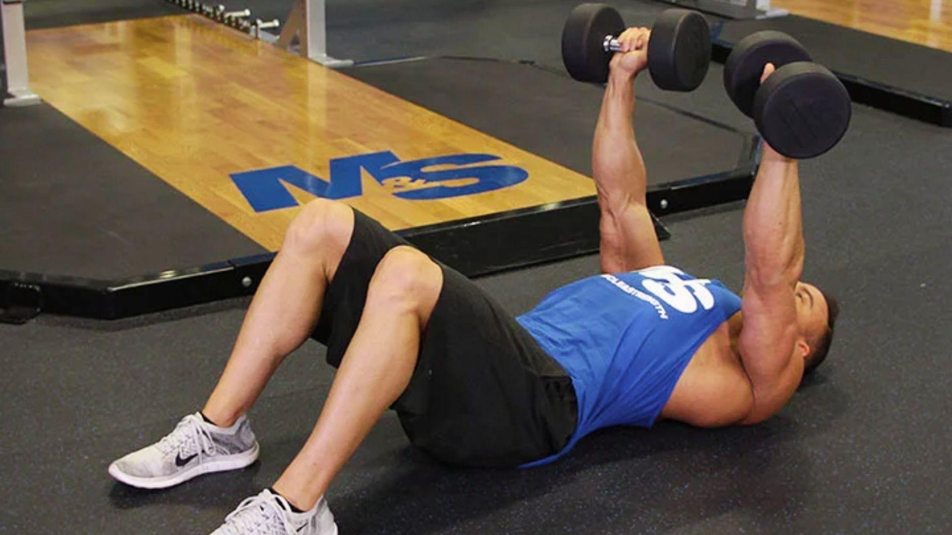 Person performing dumbbell floor press lying on the floor for chest strength and shoulder-friendly training