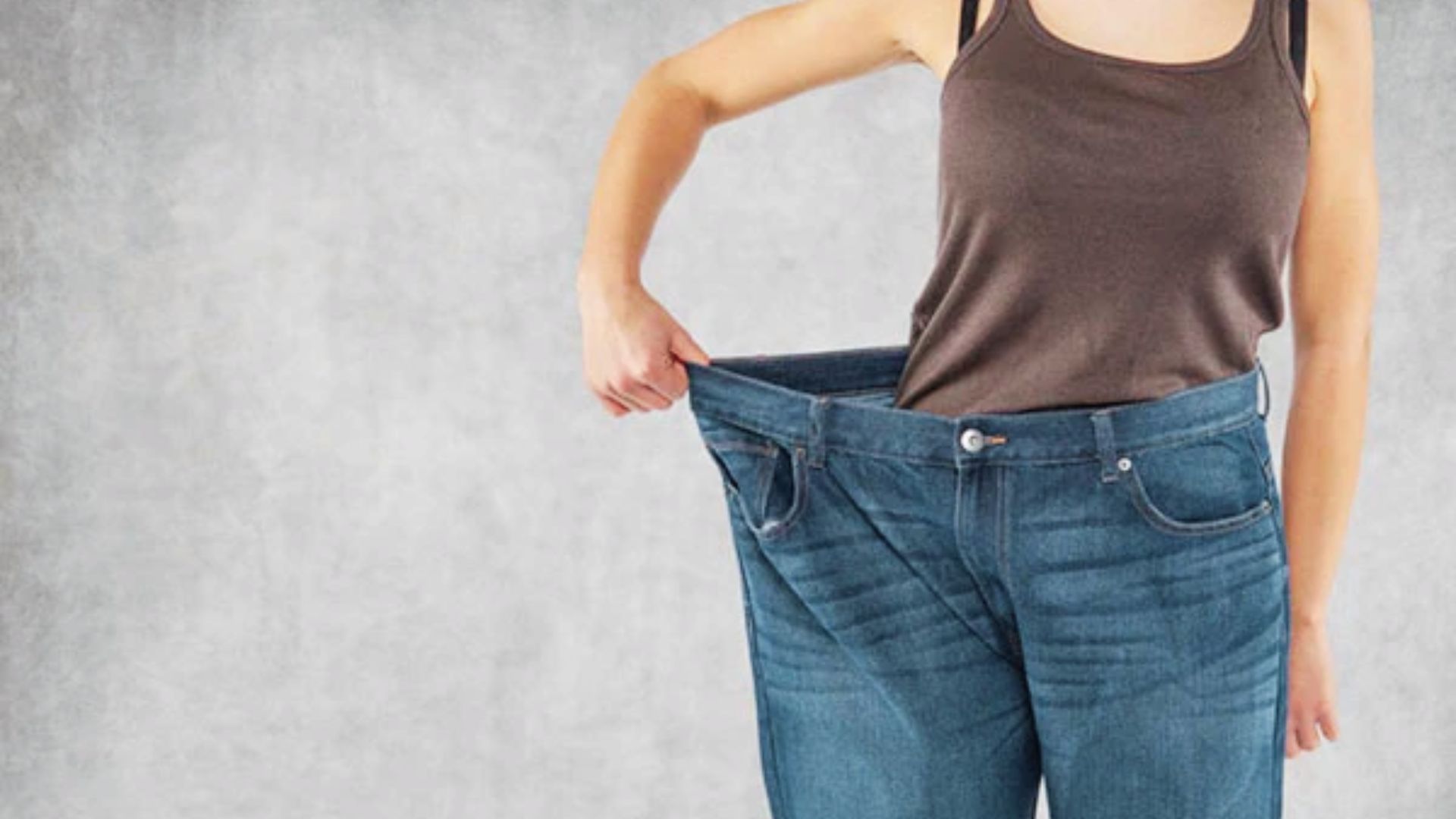 Woman checking the loose fit of her pants after weight loss, showing changes in body shape and appearance.