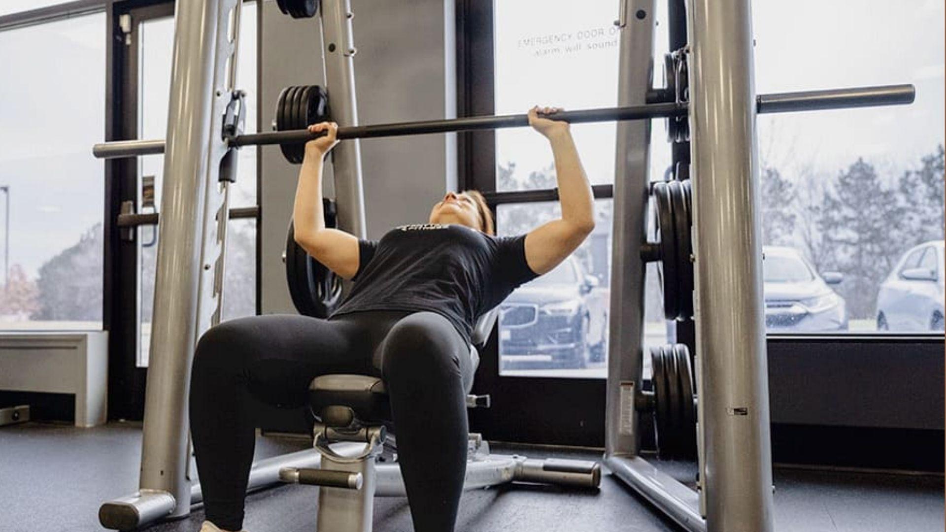 A person performing a workout on a Smith machine in the gym, showing controlled barbell movement for strength training.