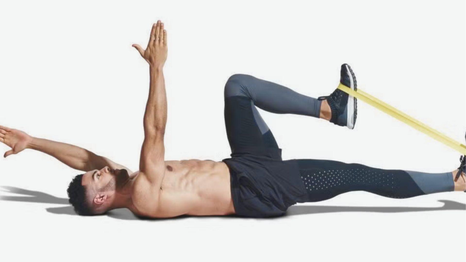 Man lying on back doing Dead Bug Exercise with resistance band around right foot.
