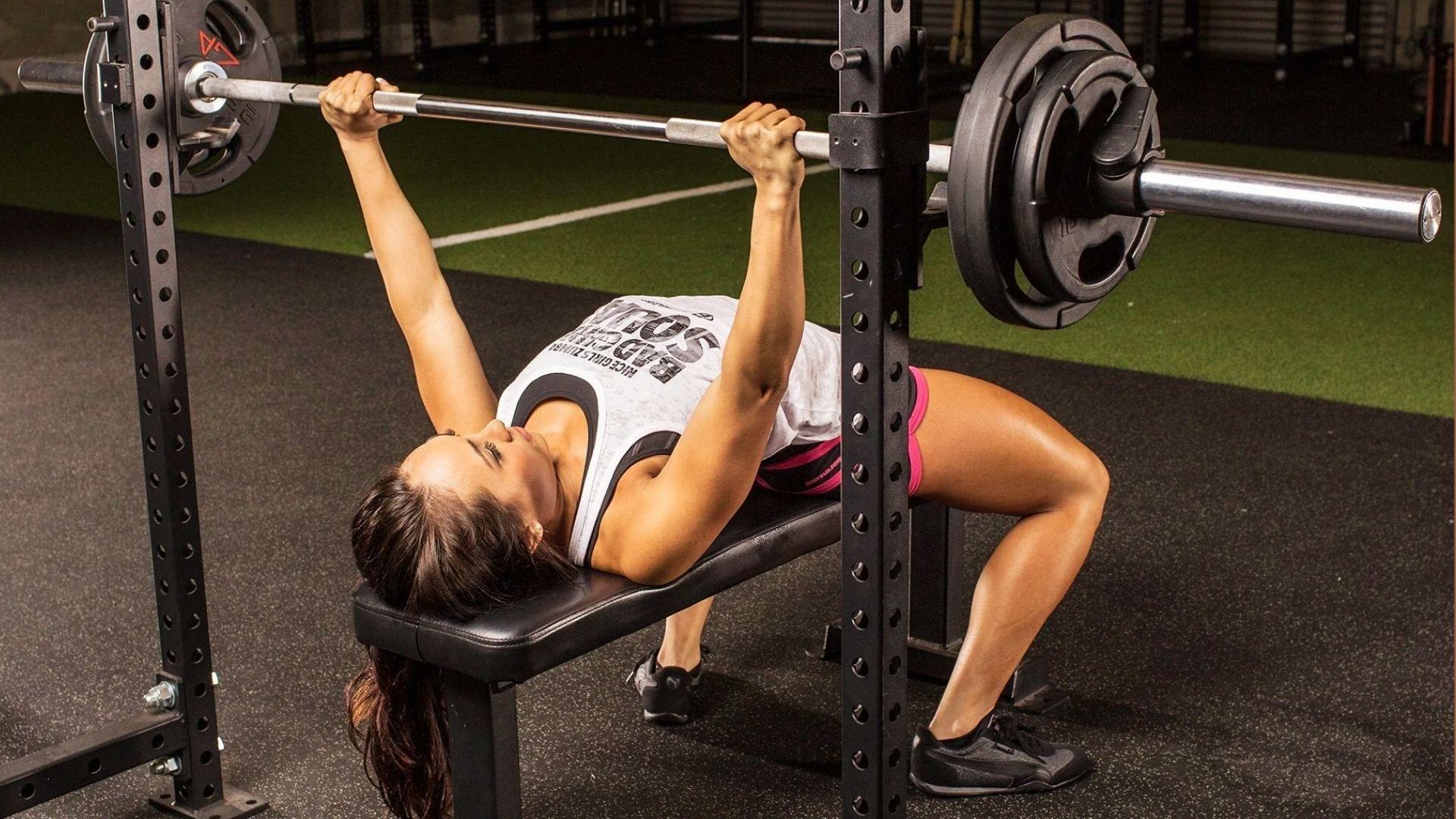 A person performing a bench press in the gym, showing proper form while measuring upper body strength performance.