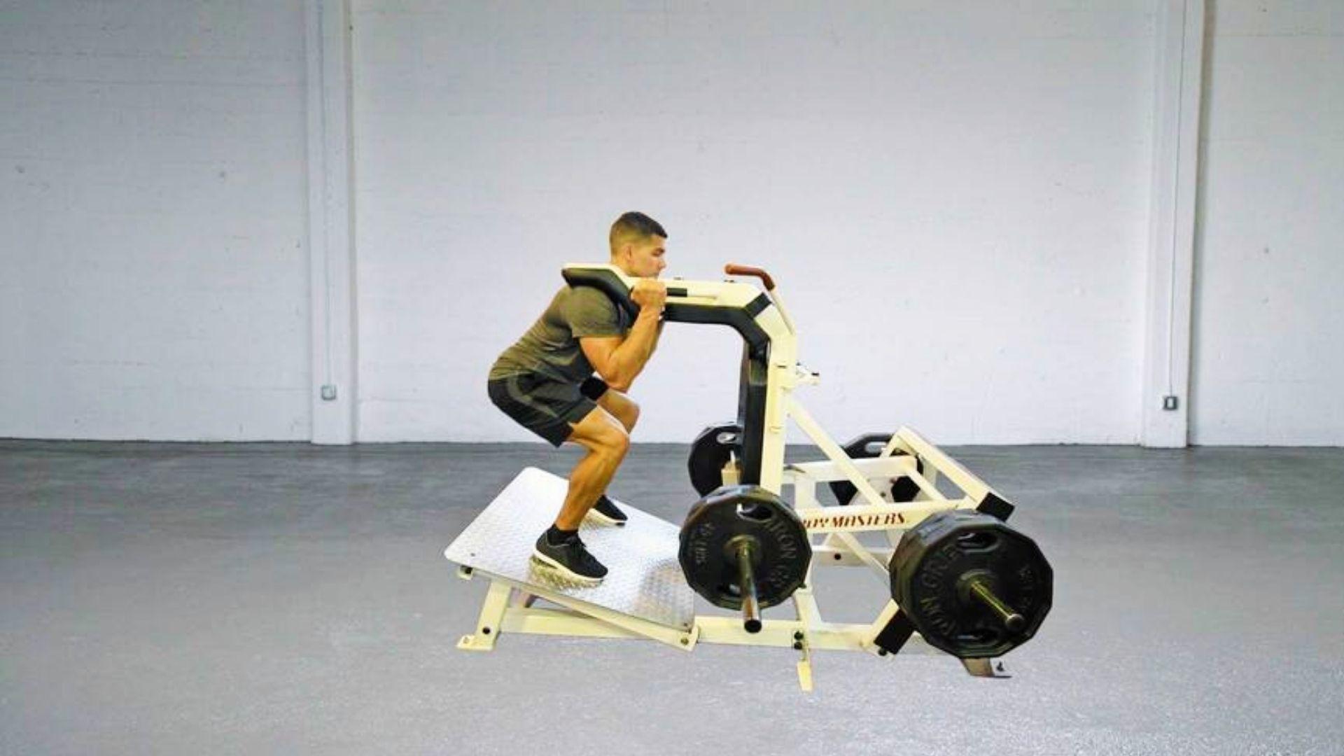 A lifter performing a hack squat on a machine with moderate weight while following a structured rep and set routine in a gym setting.