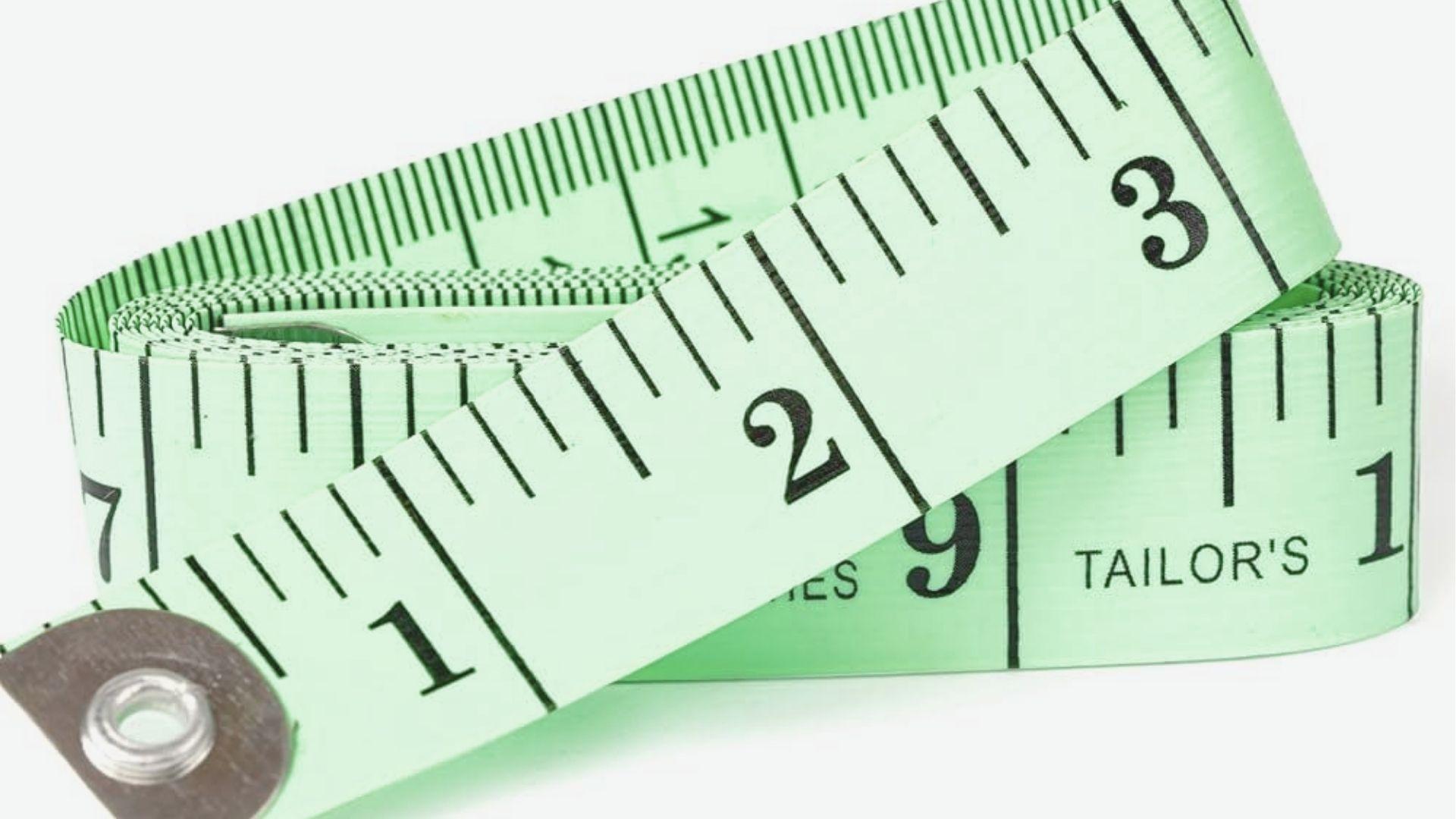 A coiled green tailor’s measuring tape with black inch markings on a white background.