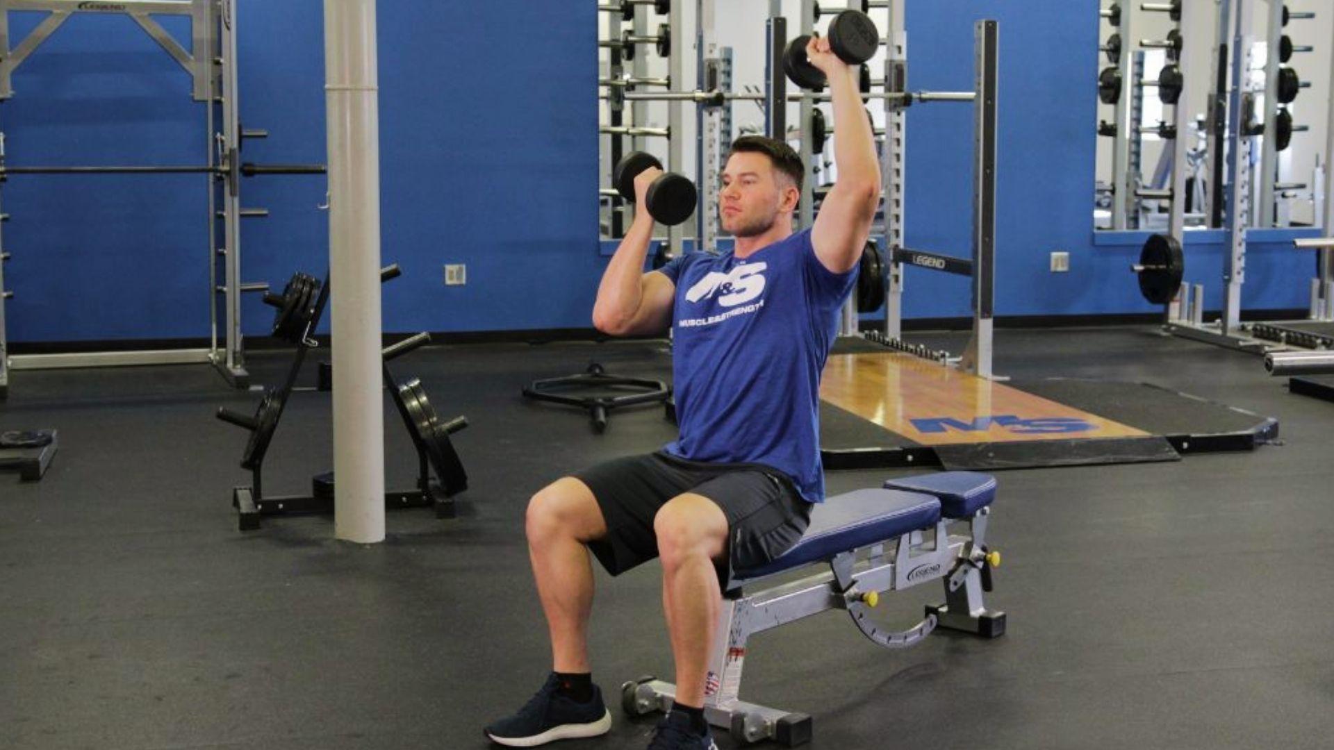 Person performing alternating dumbbell press on a bench for balanced chest strength and stability