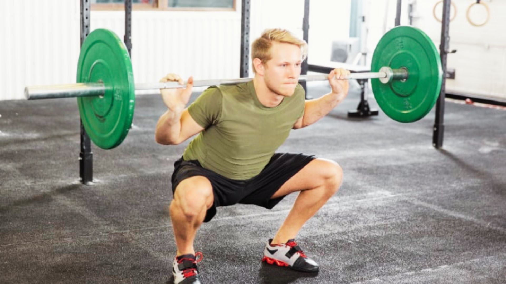 A man in olive shirt and black shorts doing Hamstrings and Glutes Leg Workout