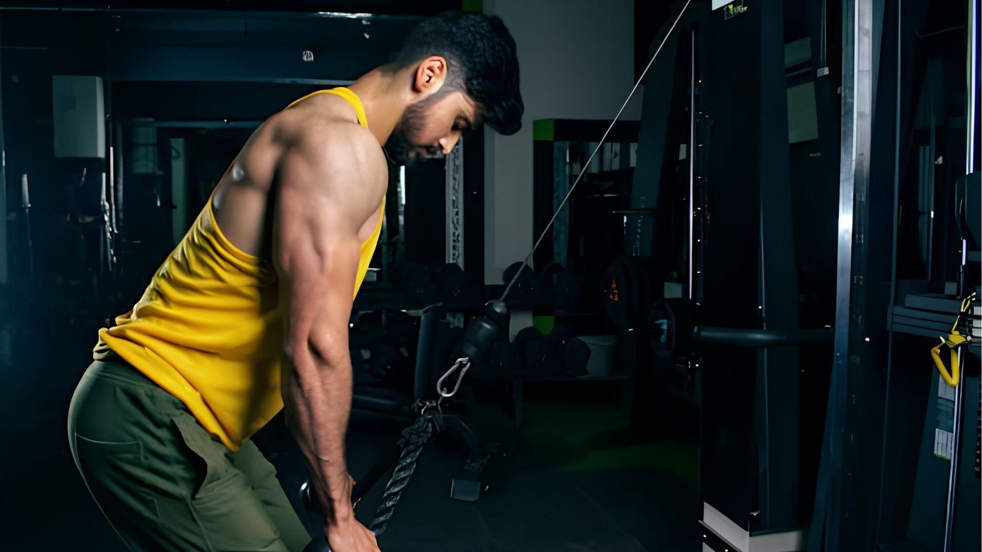 Person performing a triceps exercise with dumbbells in a gym.