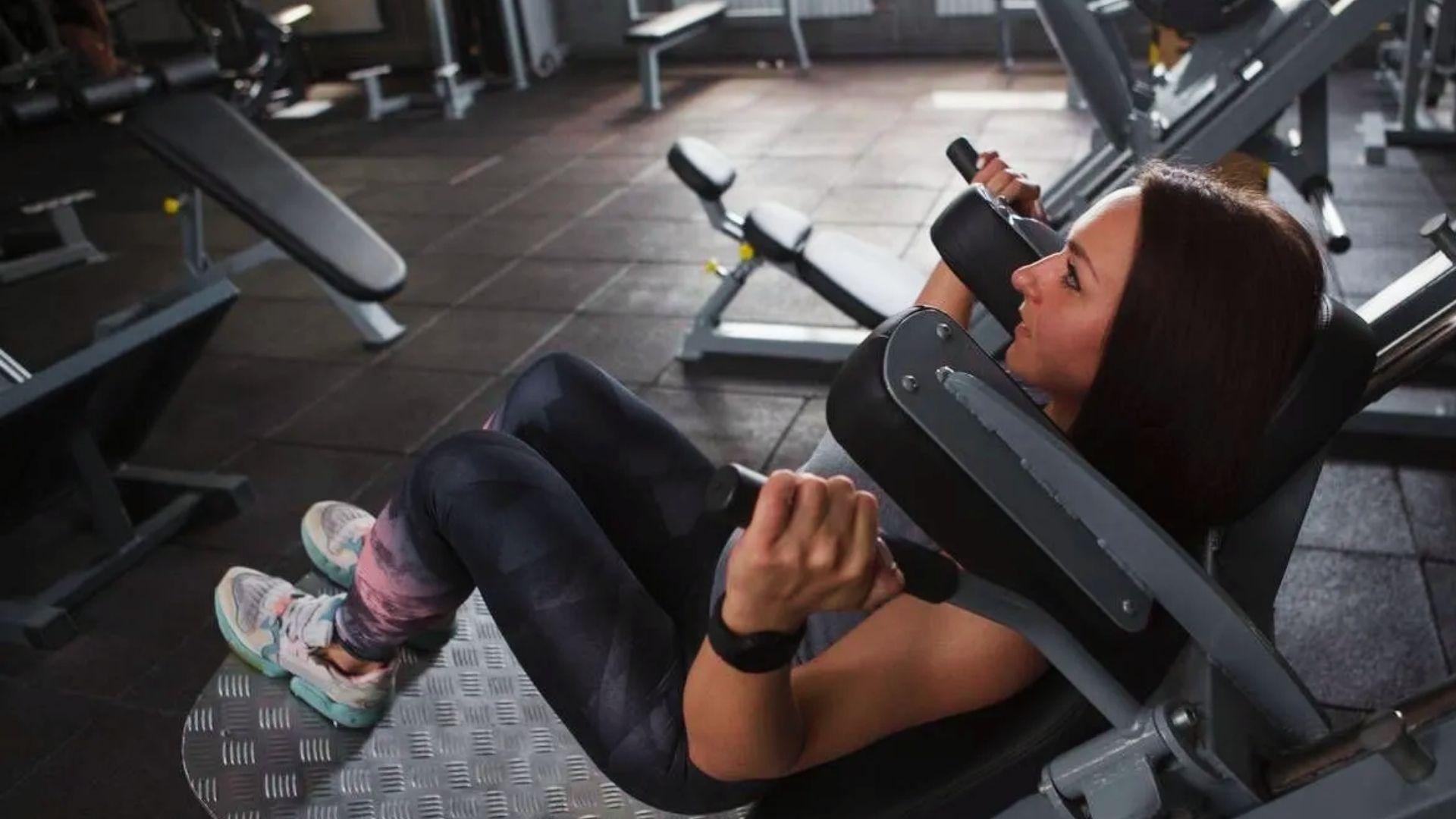 Gym athlete performing a hack squat on a machine with heavy weight, demonstrating proper depth and controlled movement.