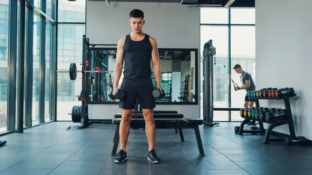 Setting up dumbbells and bench for Bulgarian split squats.