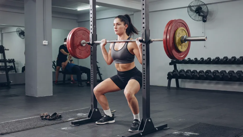 Female athlete performing a barbell back squat.