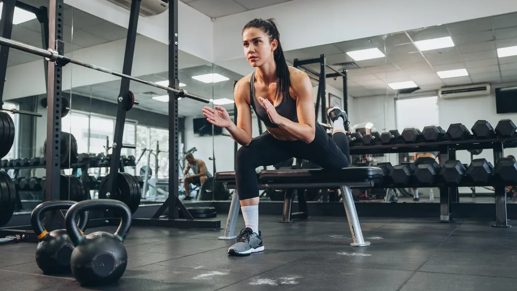 Woman performing a Bulgarian split squat using a bench.