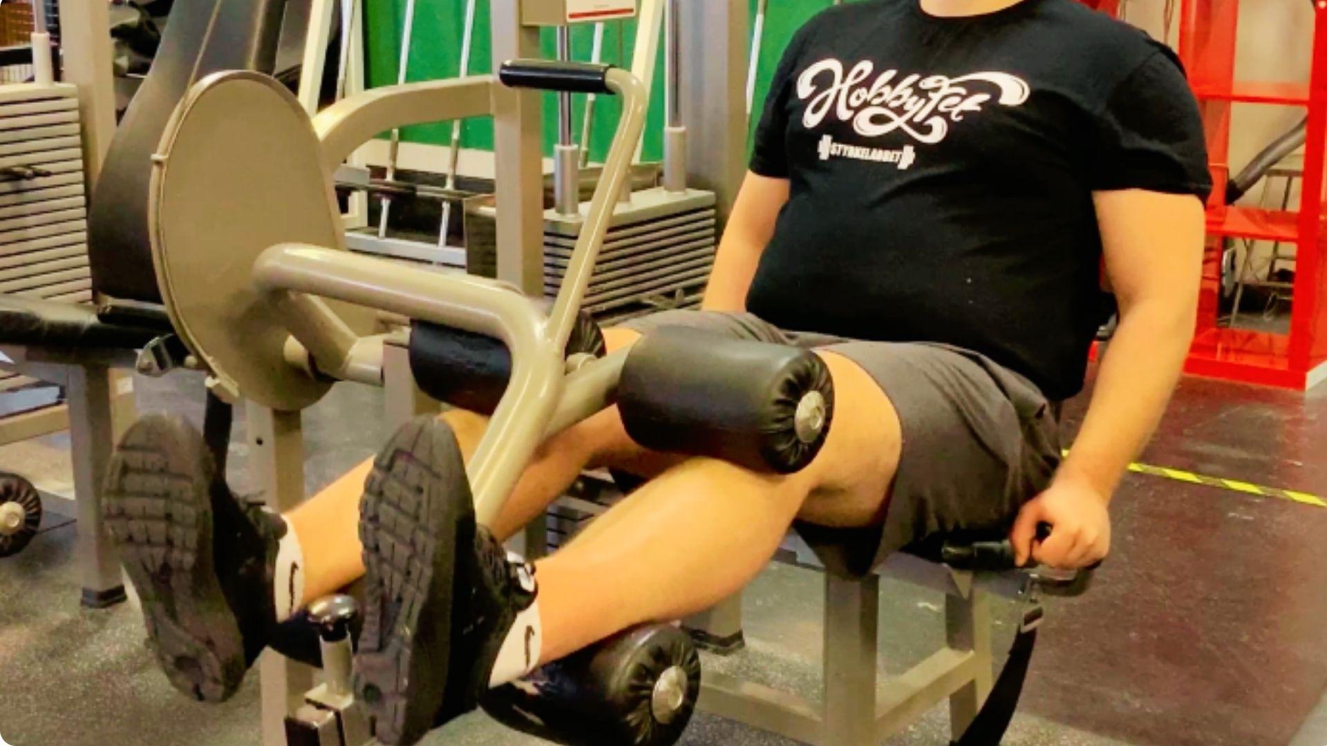 Athlete using a seated leg curl machine to target the hamstrings through controlled knee flexion.
