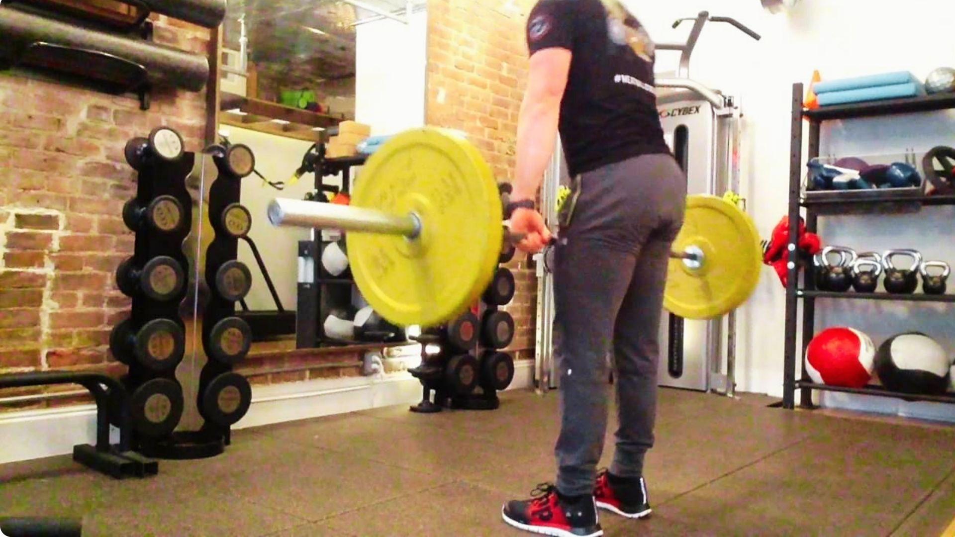Athlete performing a Romanian deadlift with a barbell, hinging at the hips to target the hamstrings and glutes.
