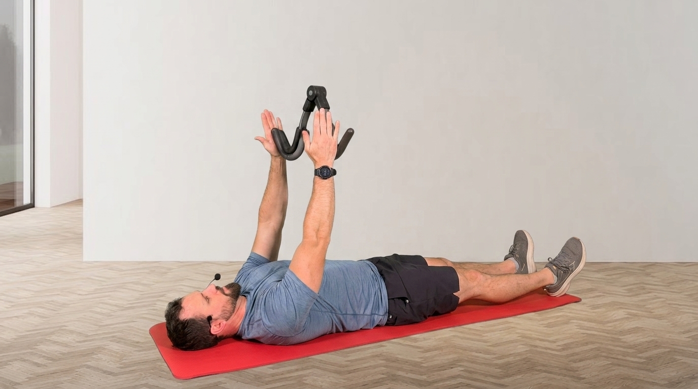 Man lying on red mat holds Thigh Master overhead to engage shoulders and core muscles