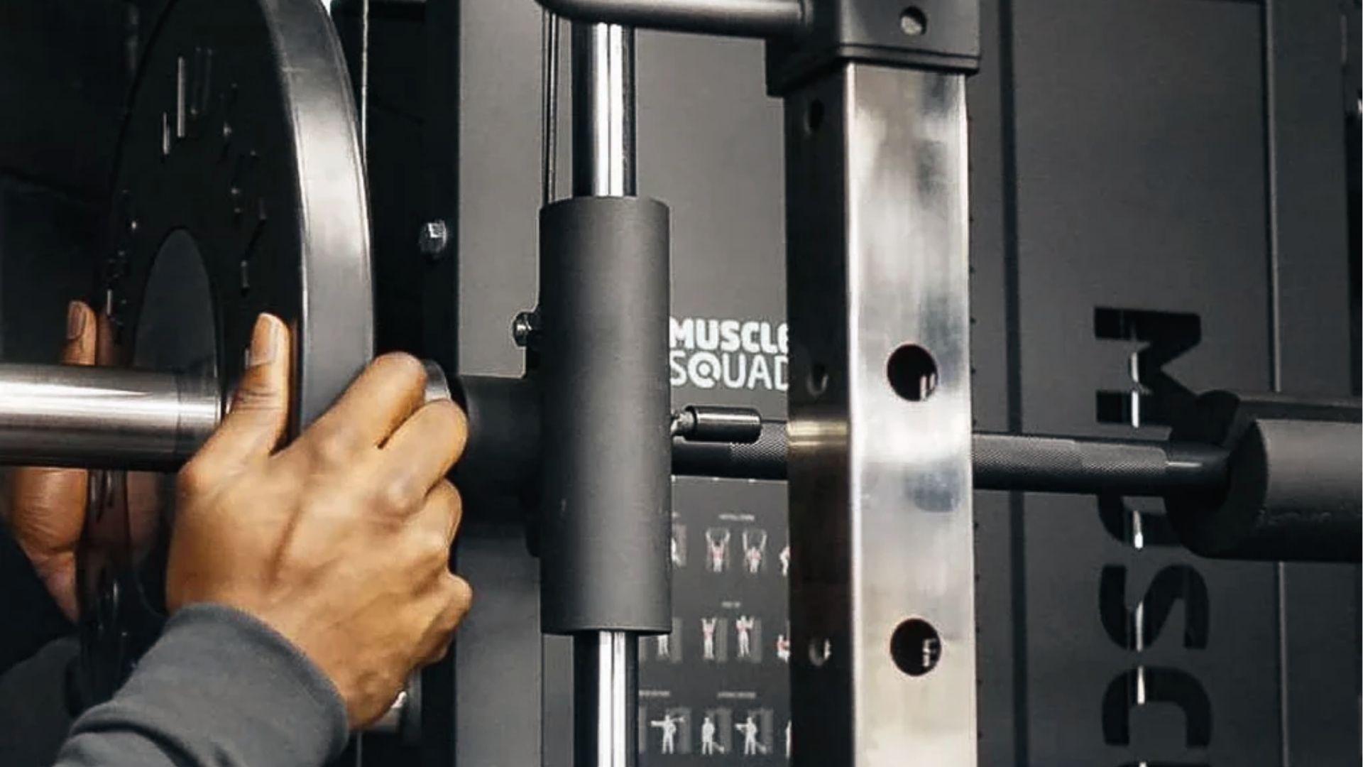 Closeup of hands loading plate on Smith machine bar demonstrating Planet Fitness bar weight.