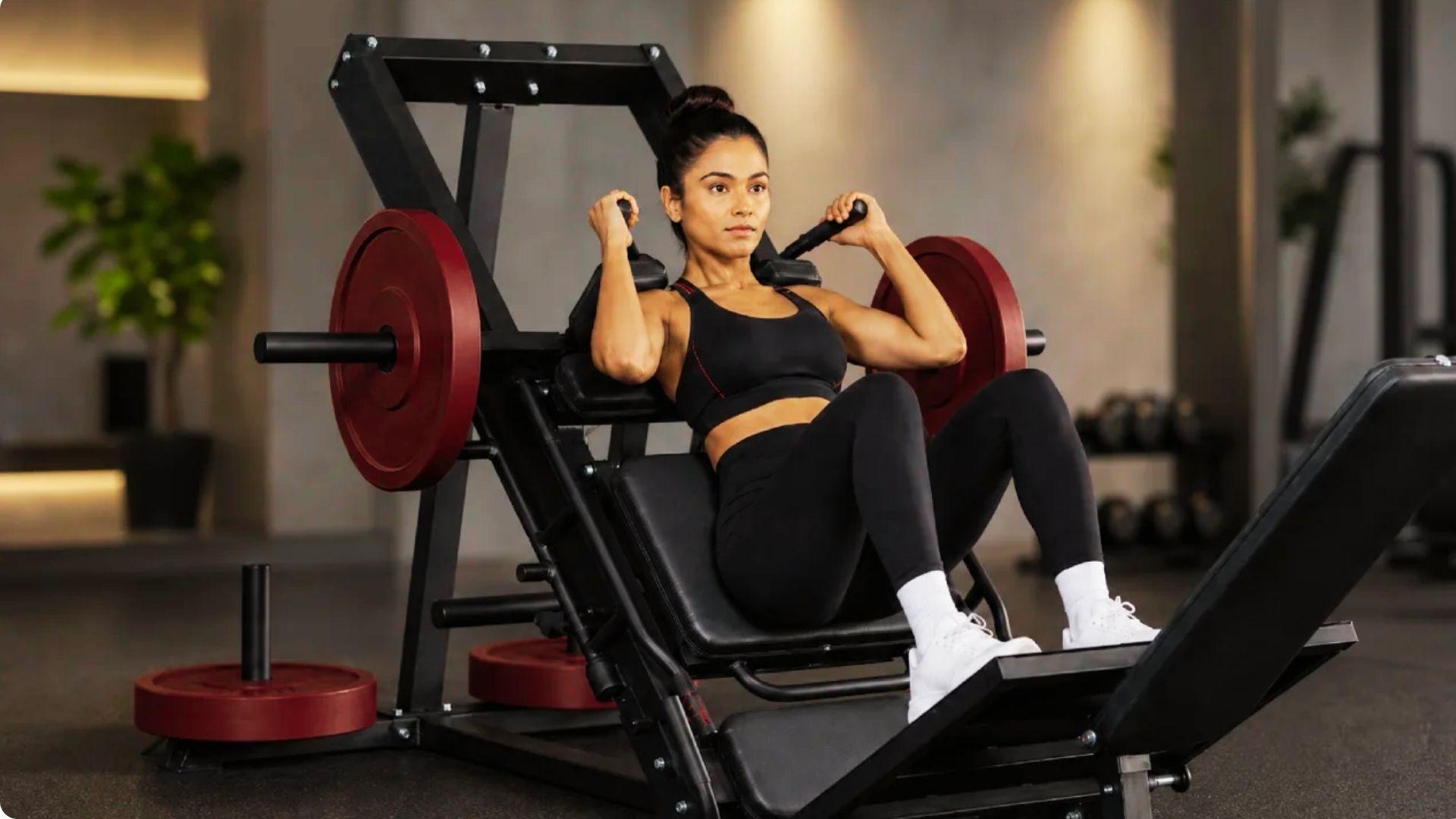 Gym member using a hack squat machine to strengthen the quadriceps, glutes, and lower body.