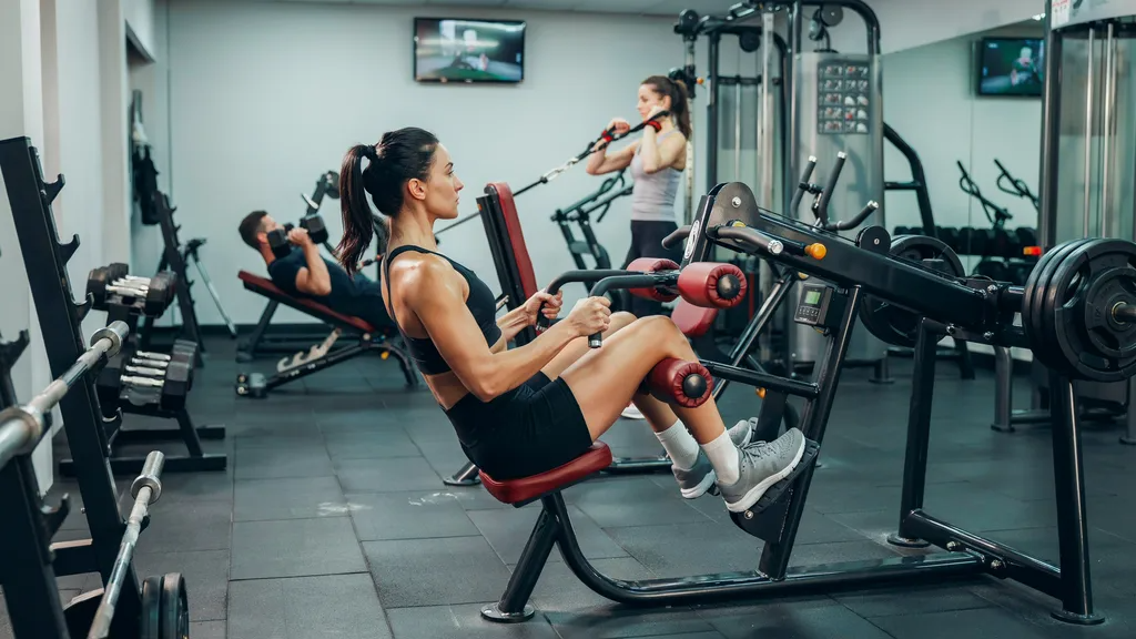 Woman using a seated hamstring curl machine.