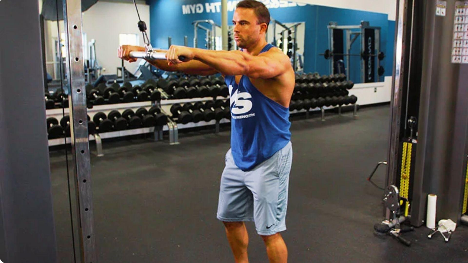 Athlete using a cable machine to perform straight arm pulldowns for lat and front lever strength development.