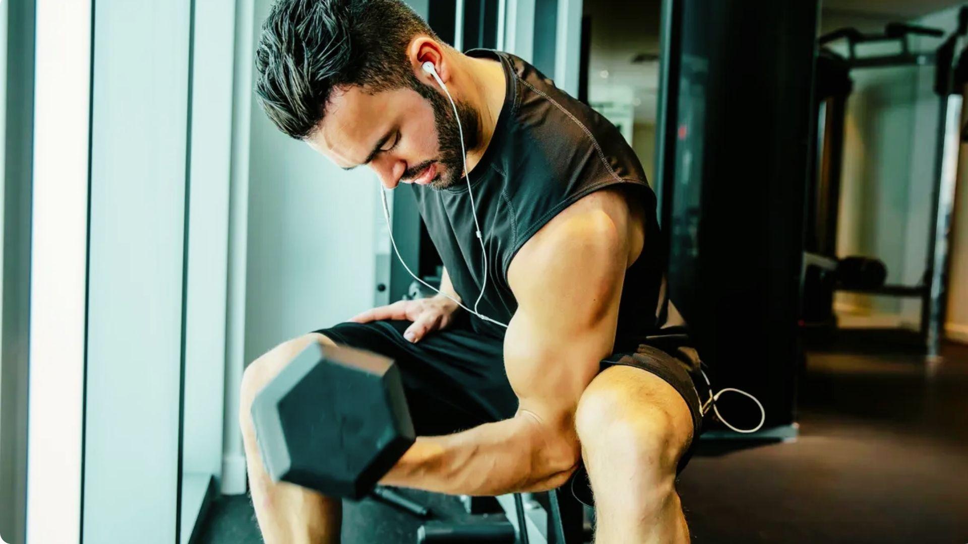Athlete performing bicep curls with visibly pumped arm muscles during a gym workout.