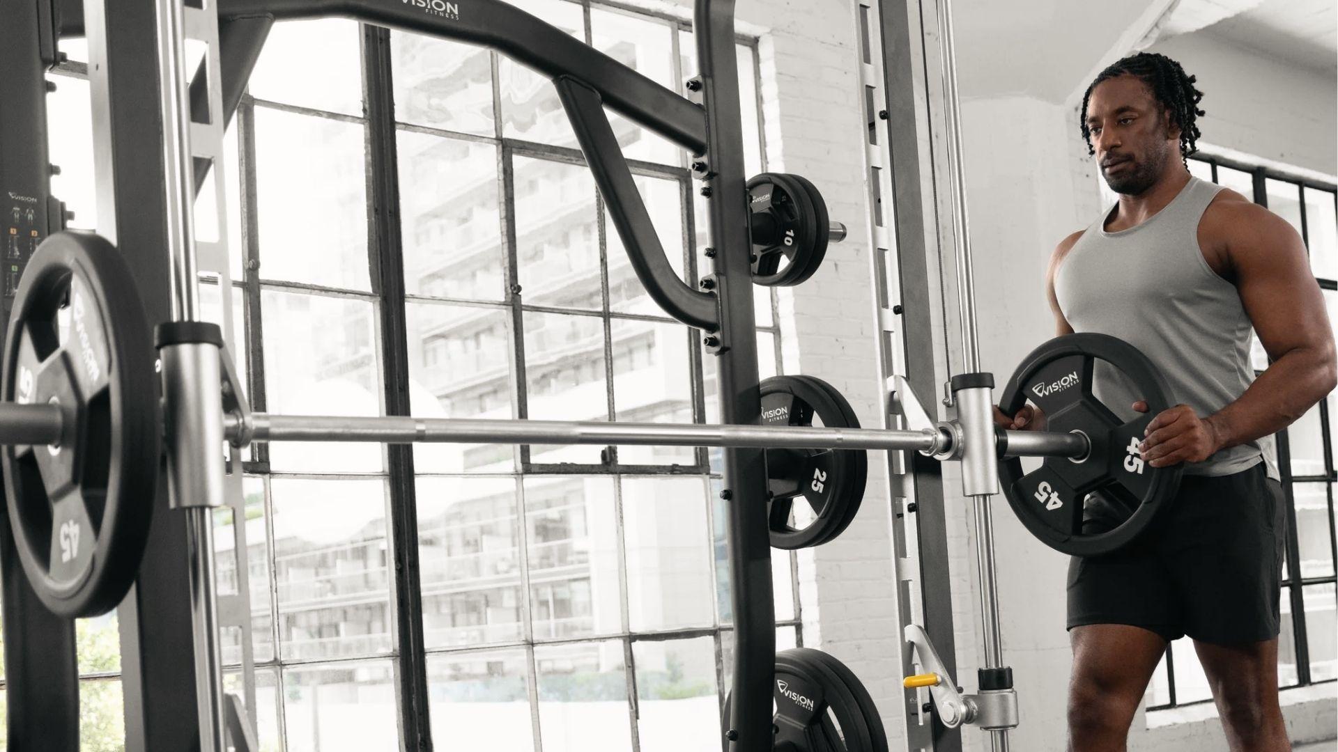 The man in the tank top adds a 45 lb plate to Smith machine bar to calculate total weight at Planet Fitness.
