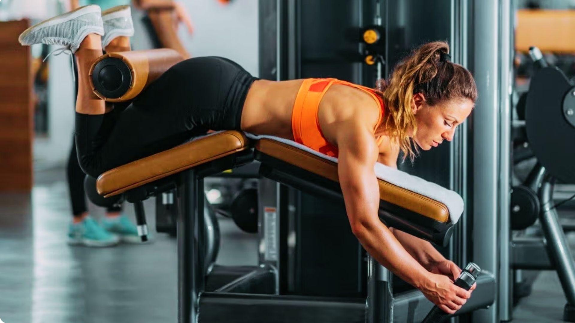 Person performing a lying leg curl on a machine, curling the legs upward to strengthen the hamstrings.