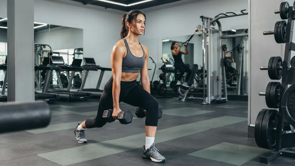 Woman performing walking lunges with dumbbells.
