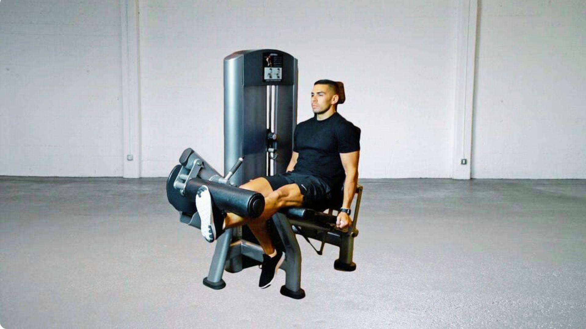 Person seated on a leg extension machine extending the knees to isolate and strengthen the quadriceps.