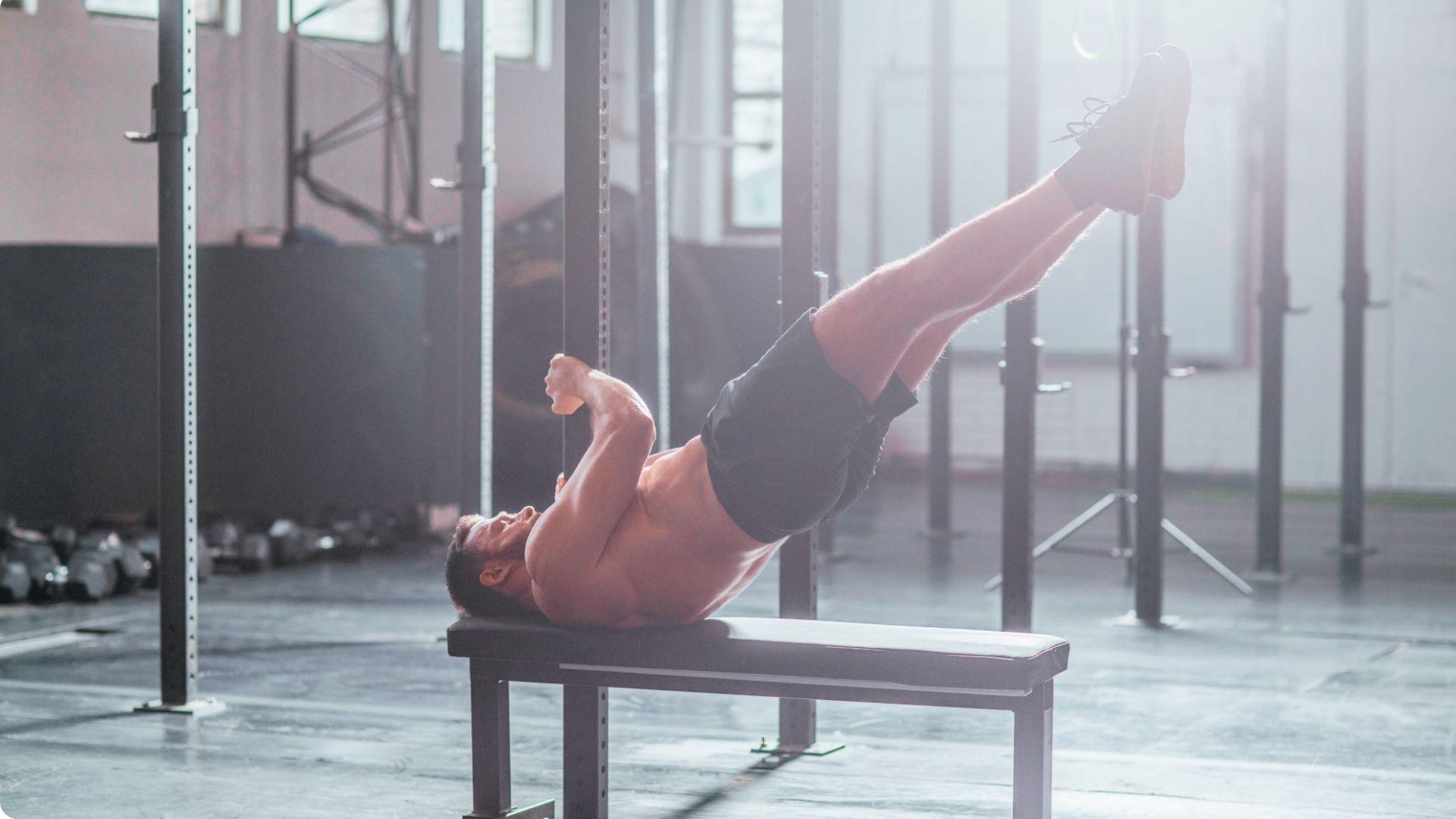 Athlete performing a dragon flag on a bench while maintaining a straight body position during the lowering phase.