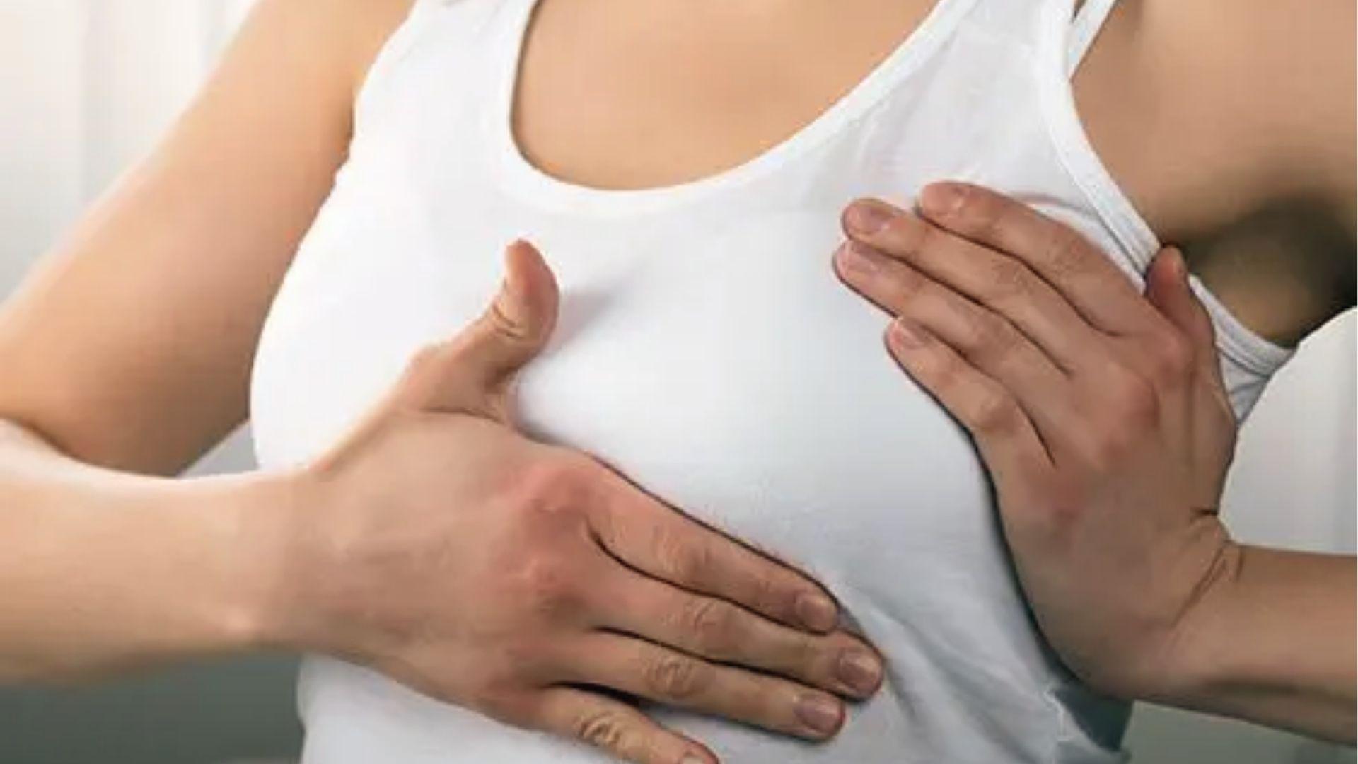 Woman placing hands on chest area showing location of pectoral muscles under breast tissue