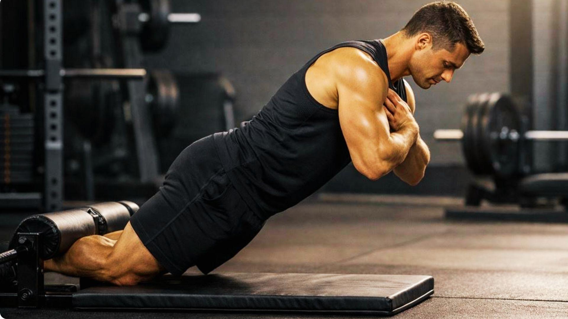Person kneeling with feet anchored, slowly lowering their body forward using hamstring strength during a Nordic curl exercise.