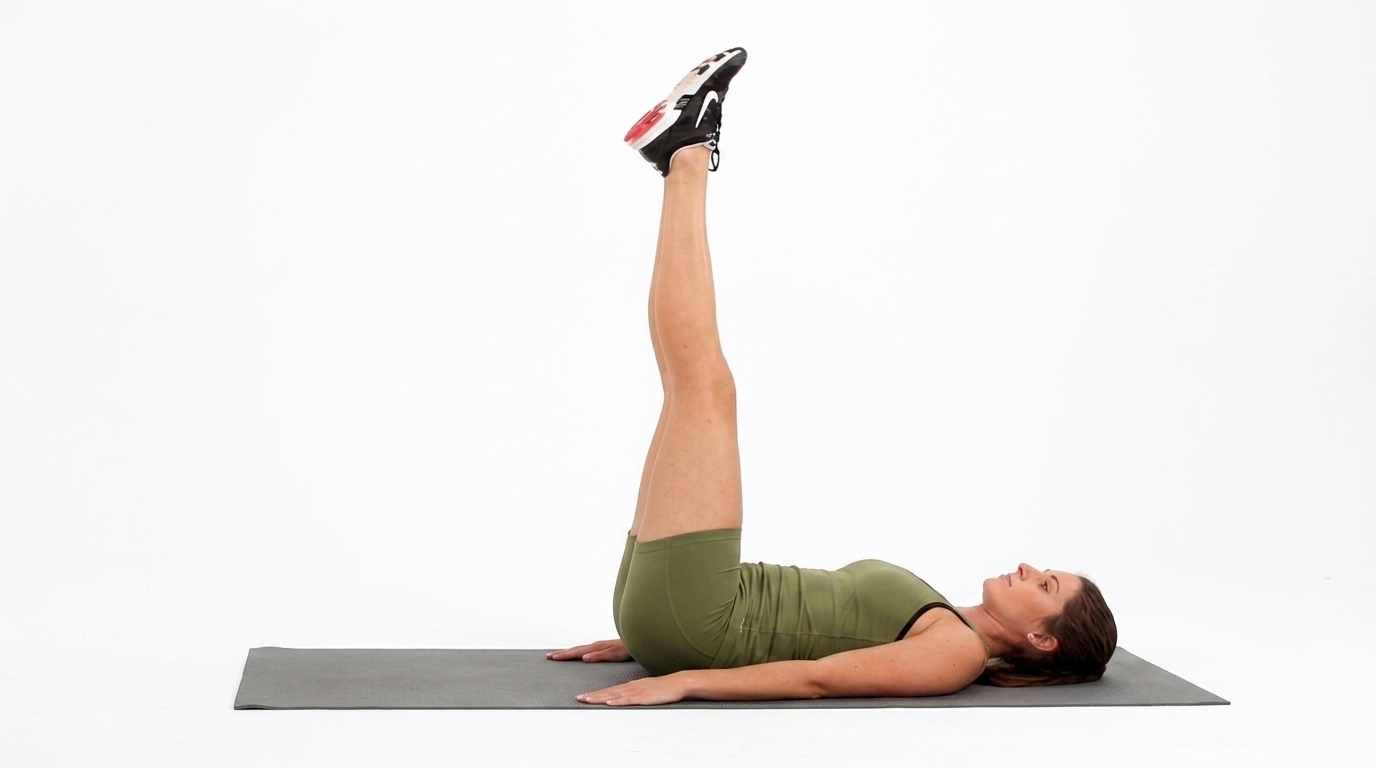 Woman demonstrating a leg raise exercise on a gray mat against a white background.
