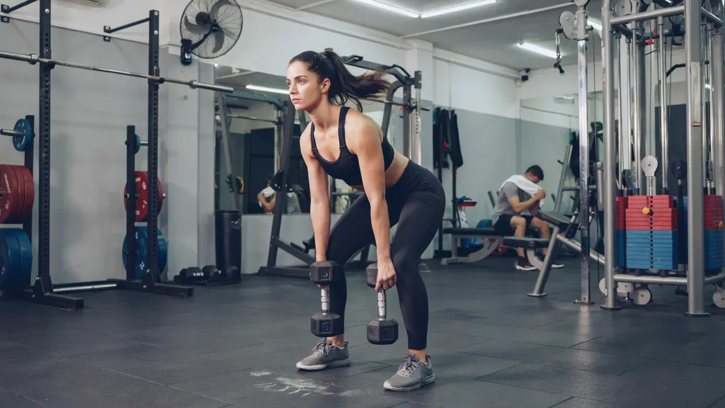 Woman performing Romanian deadlifts with proper hip hinge technique.
