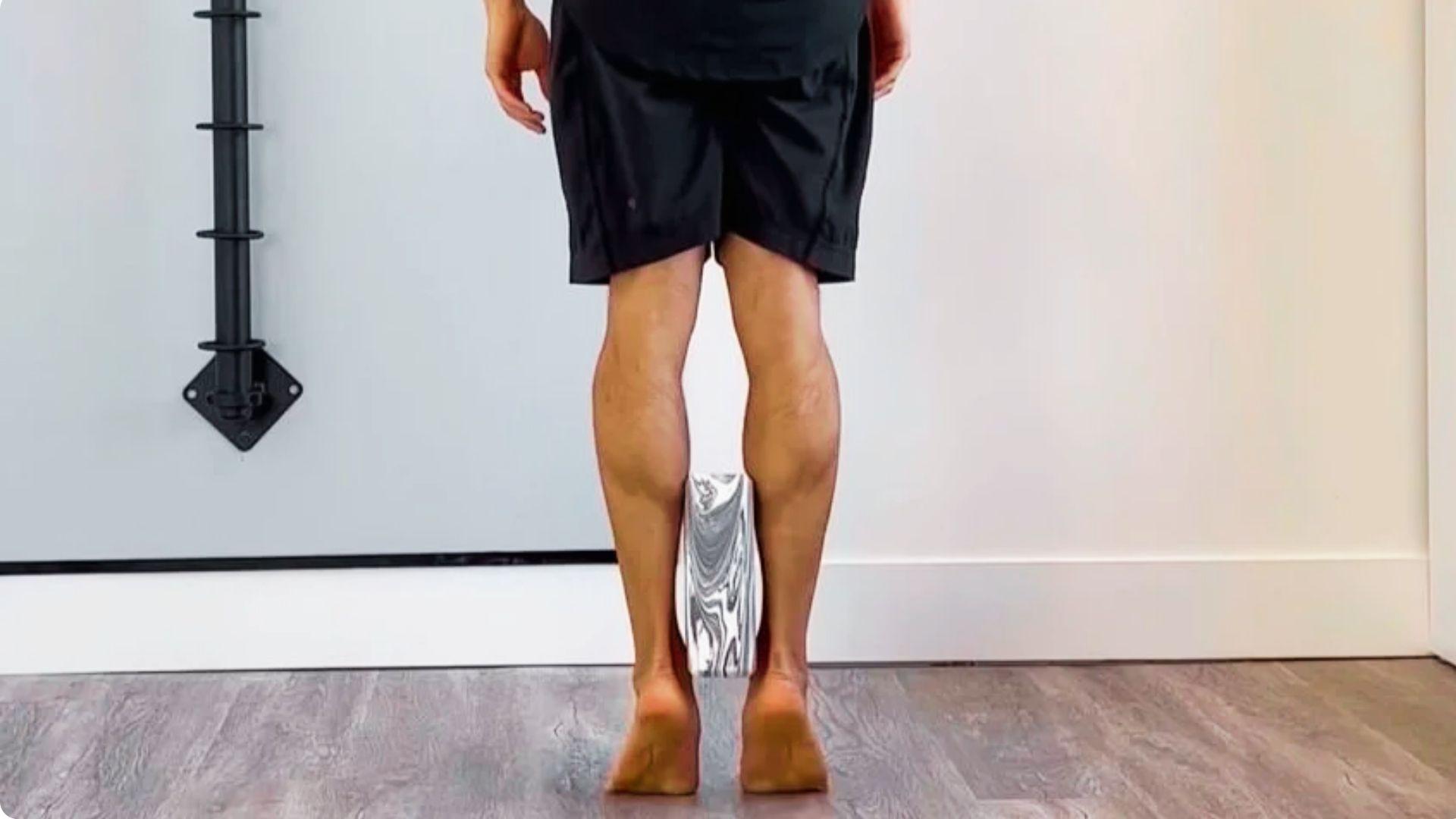 Person standing against a wall and doing heel raises exercise strengthening calf muscles and improving ankle stability