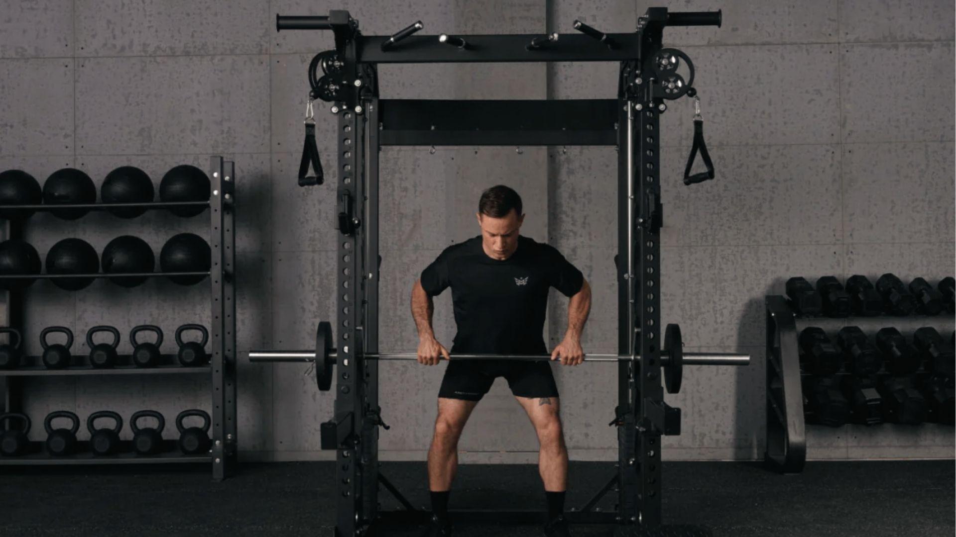 Athlete does upright rows on Smith machine showing Planet Fitness bar weight is 15 to 20 pounds.