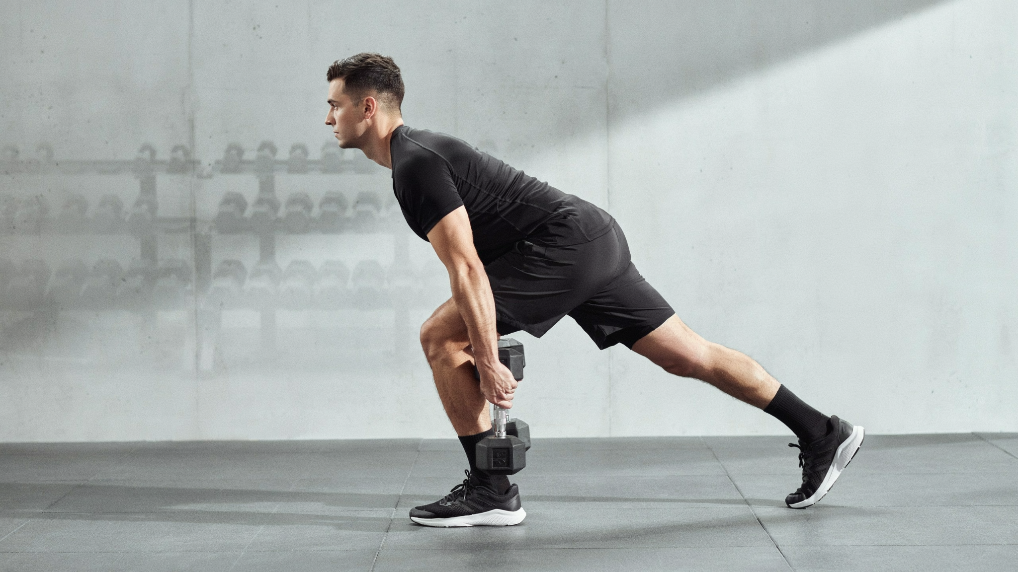 Person balancing on one leg while performing a single-leg deadlift, hinging forward with a dumbbell and extending the other leg behind for balance and strength.