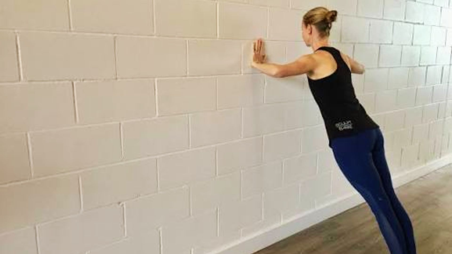 Person demonstrating proper wall push-up form on white wall