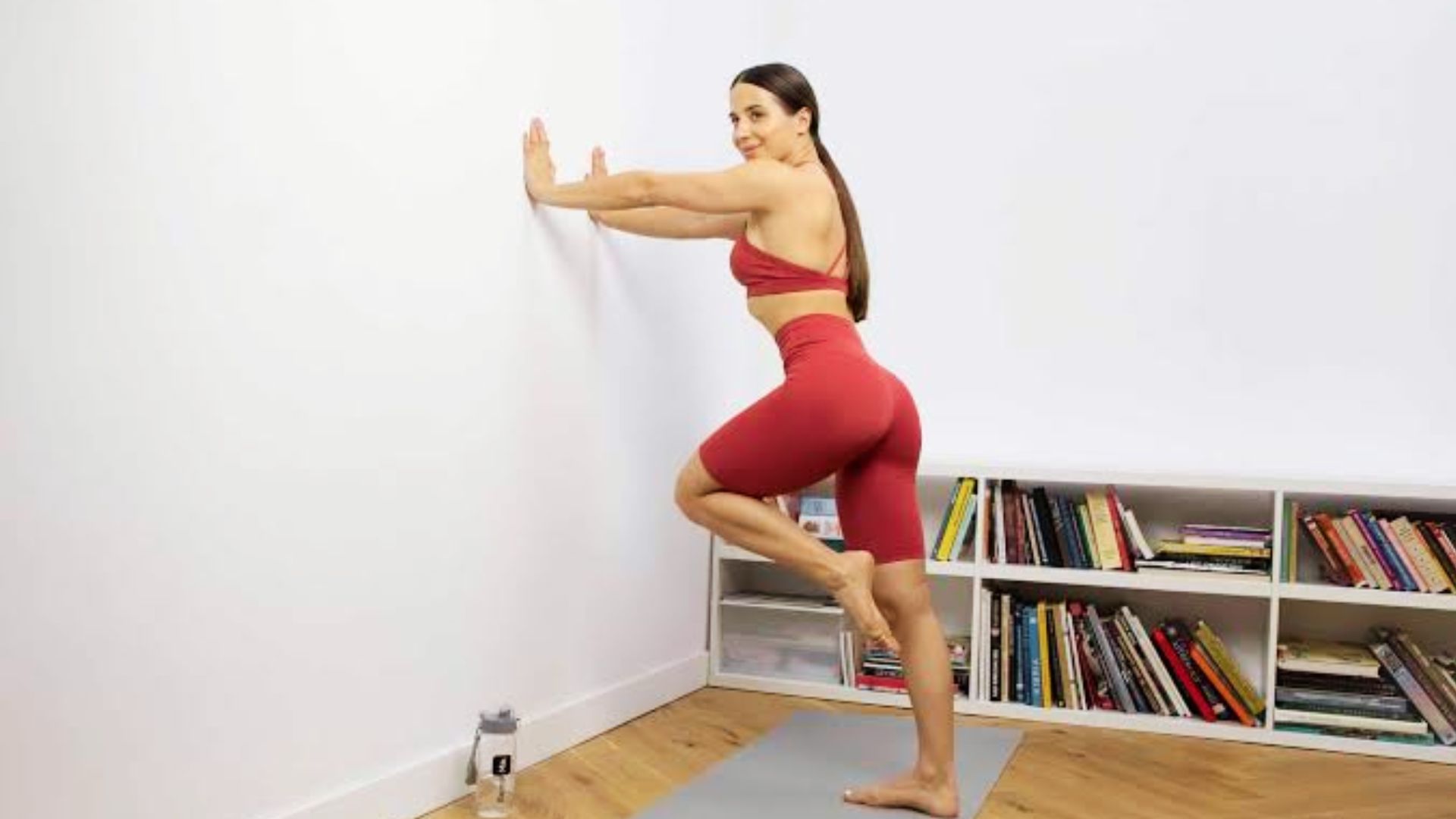 Woman doing wall push-up variation with one leg raised for balance
